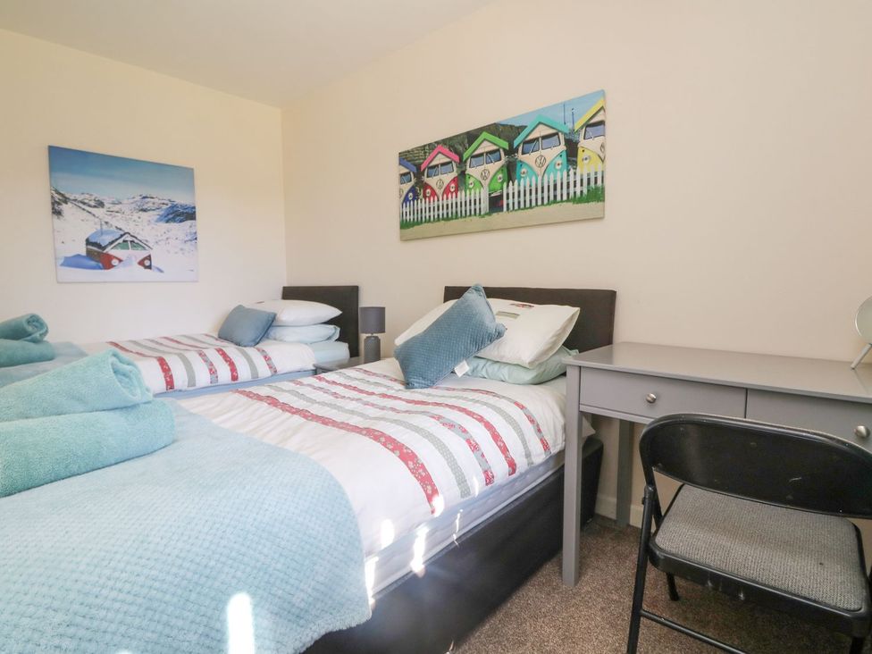 A bedroom with two beds and a desk at Honeycombe Lodge