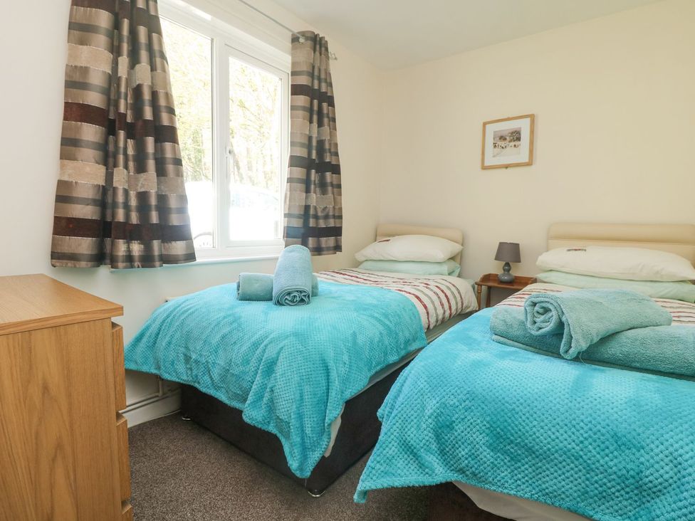 A bedroom with two single beds and a bedside table at Honeycombe Lodge