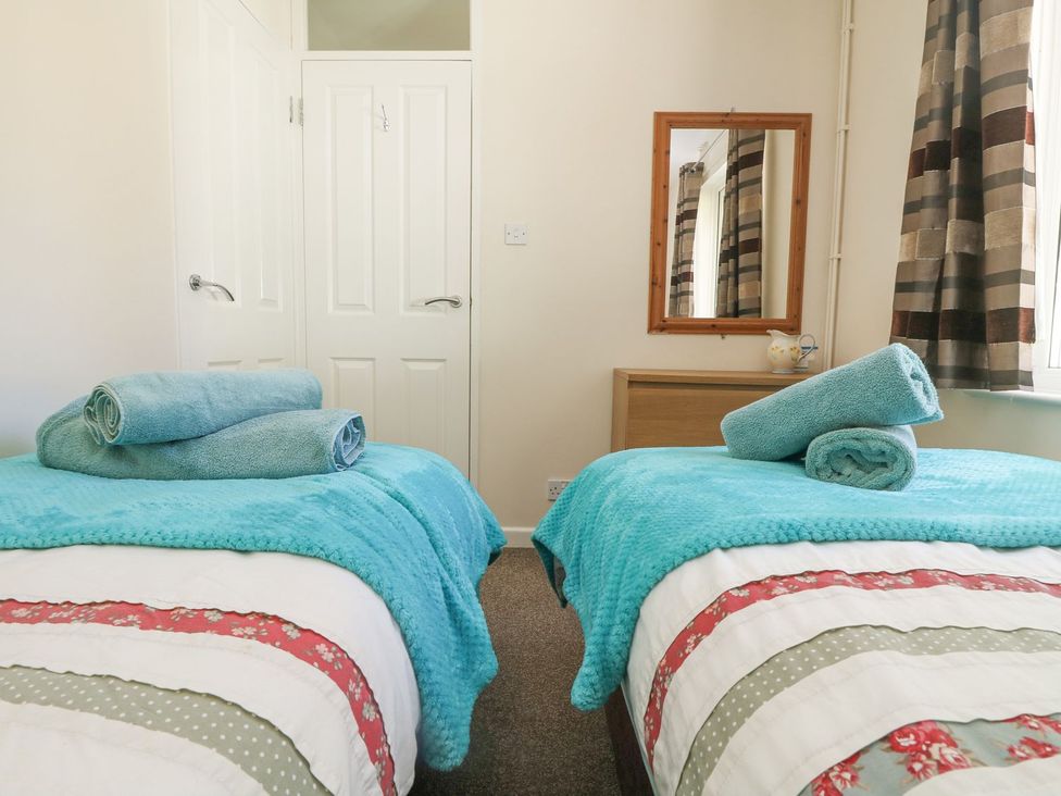 A bedroom with two beds and towels arranged at Honeycombe Lodge
