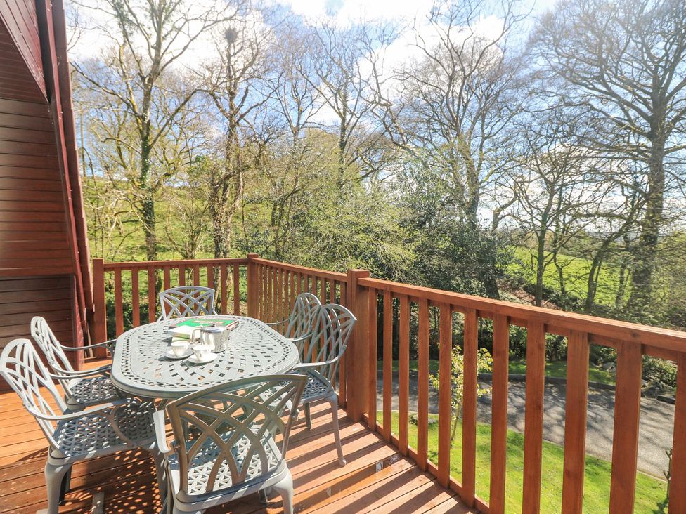 An outdoor deck with a table and chairs at Honeycombe Lodge