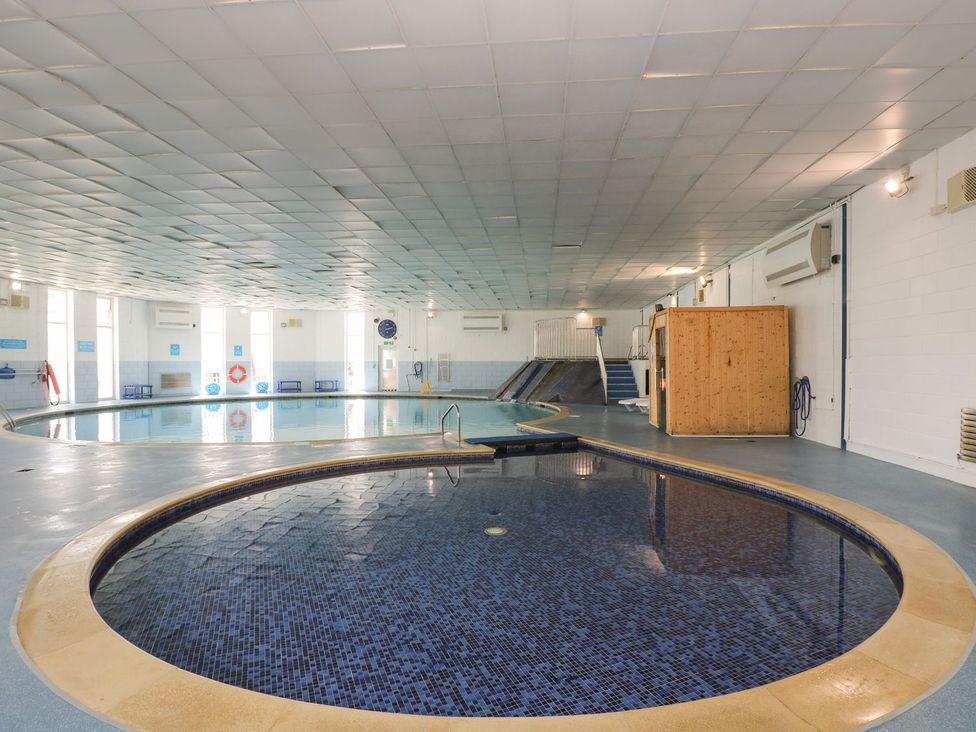 An indoor pool area with a round pool and a wooden cabin at Honeycombe Lodge 