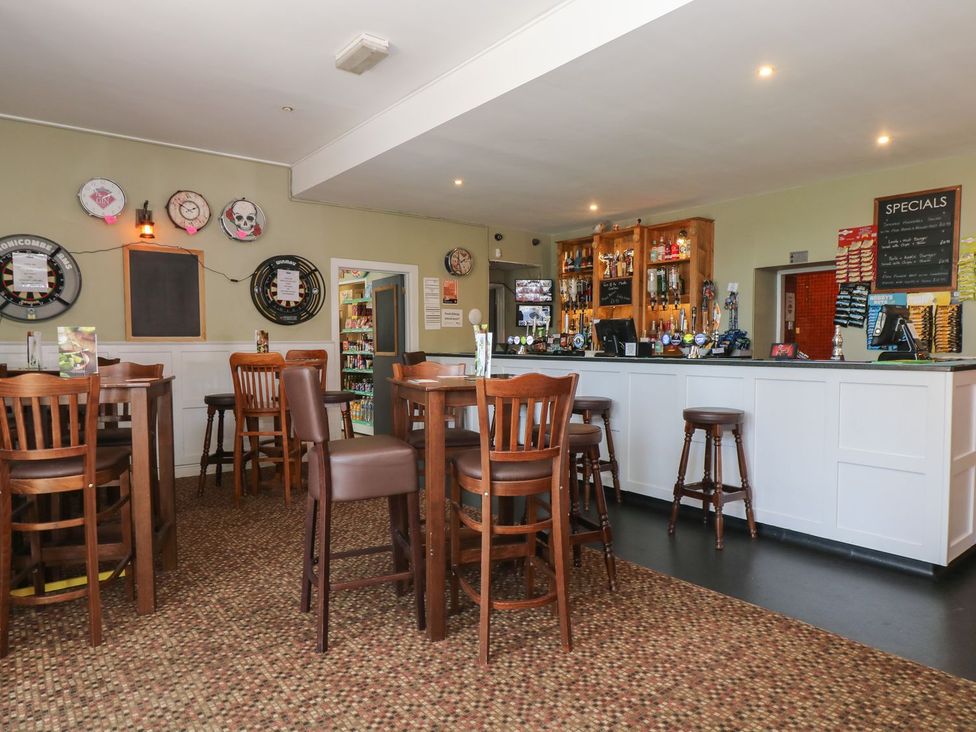 A bar area with high tables and chairs at Honeycombe Lodge
