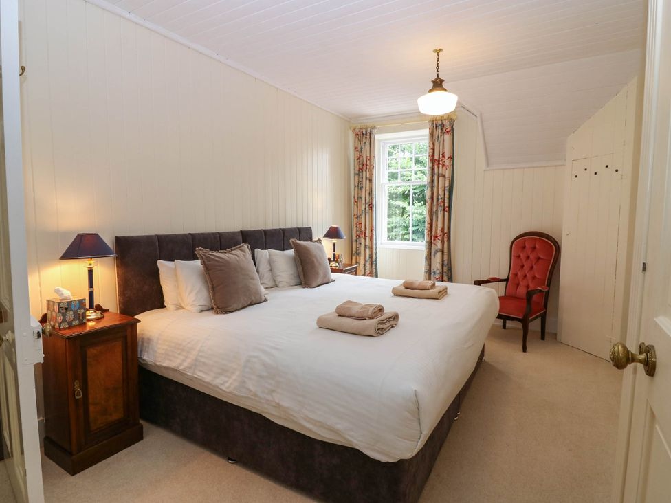 A bedroom with a large bed and side table at West House in Perth