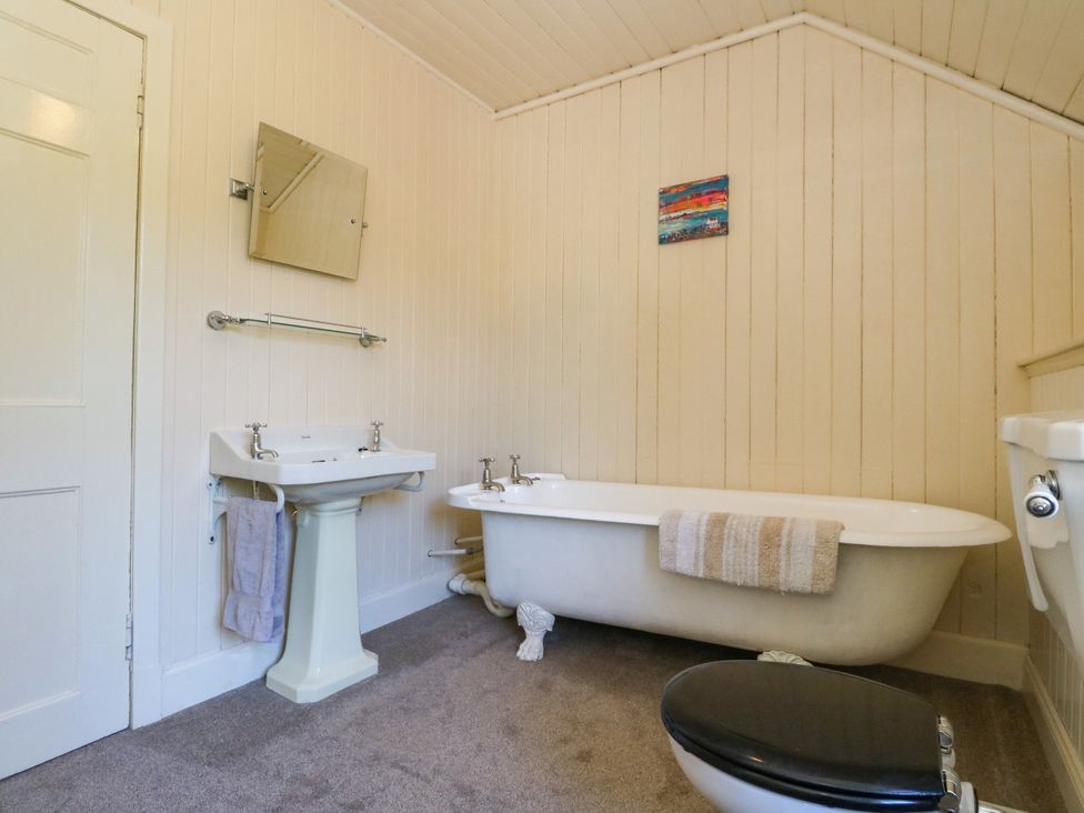 A bathroom with a bathtub, sink, toilet, and mirror at West House in Stanley