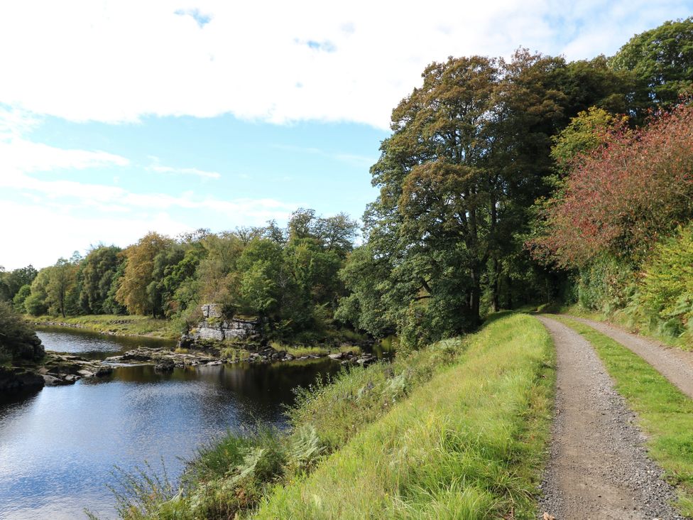 A pathway along a river with trees in the background at West House in Stanley