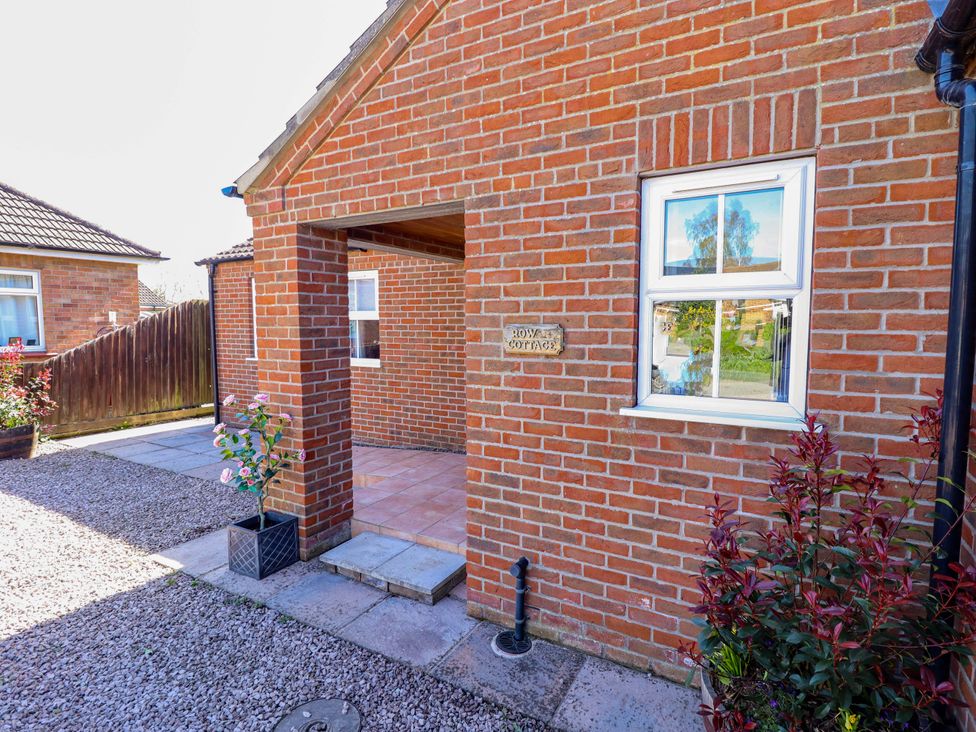 An outdoor entryway with a brick wall and flower pots at Rowan Cottage Boston