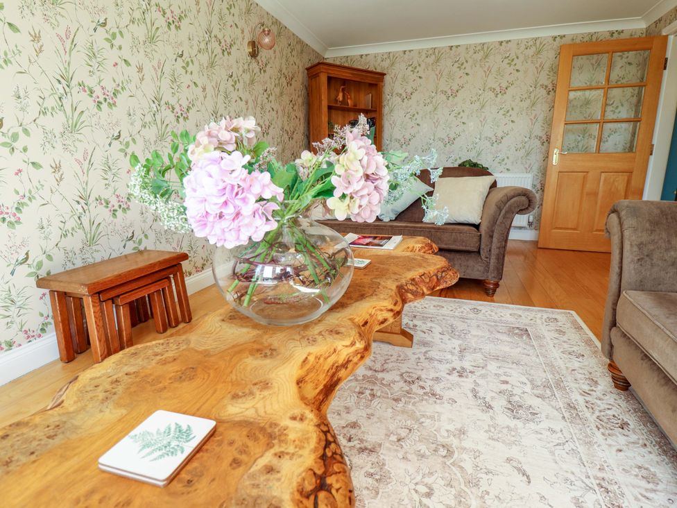 A living room with a wooden table and flower arrangement at Rowan Cottage in Boston