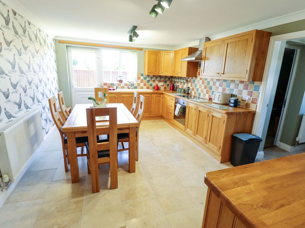 A kitchen with wooden cabinets and a dining table at Rowan Cottage in Boston