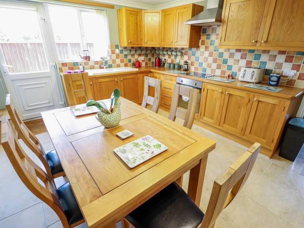 A kitchen with wooden cabinets and a dining table at Rowan Cottage in Boston