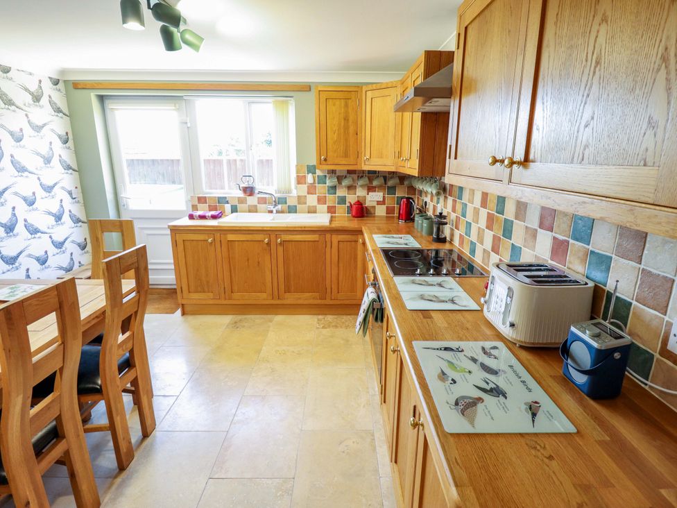 A kitchen with wooden cabinets and appliances at Rowan Cottage in Boston