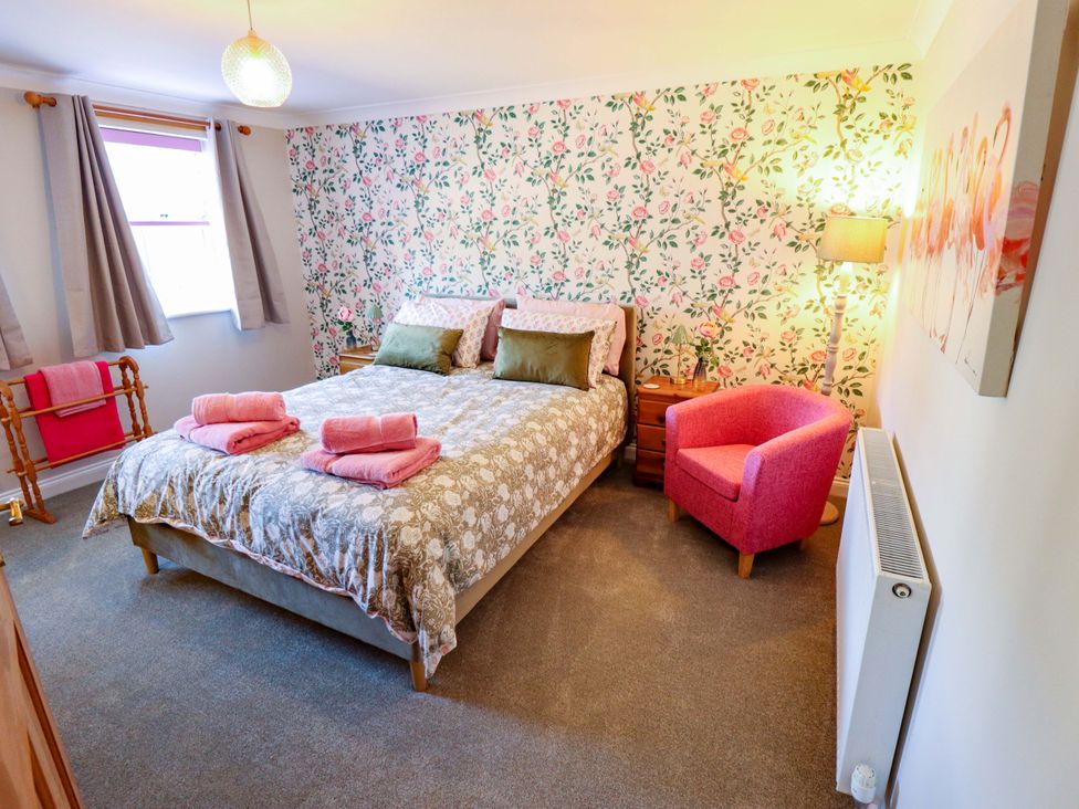 A bedroom with a bed and chair at Rowan Cottage in Boston