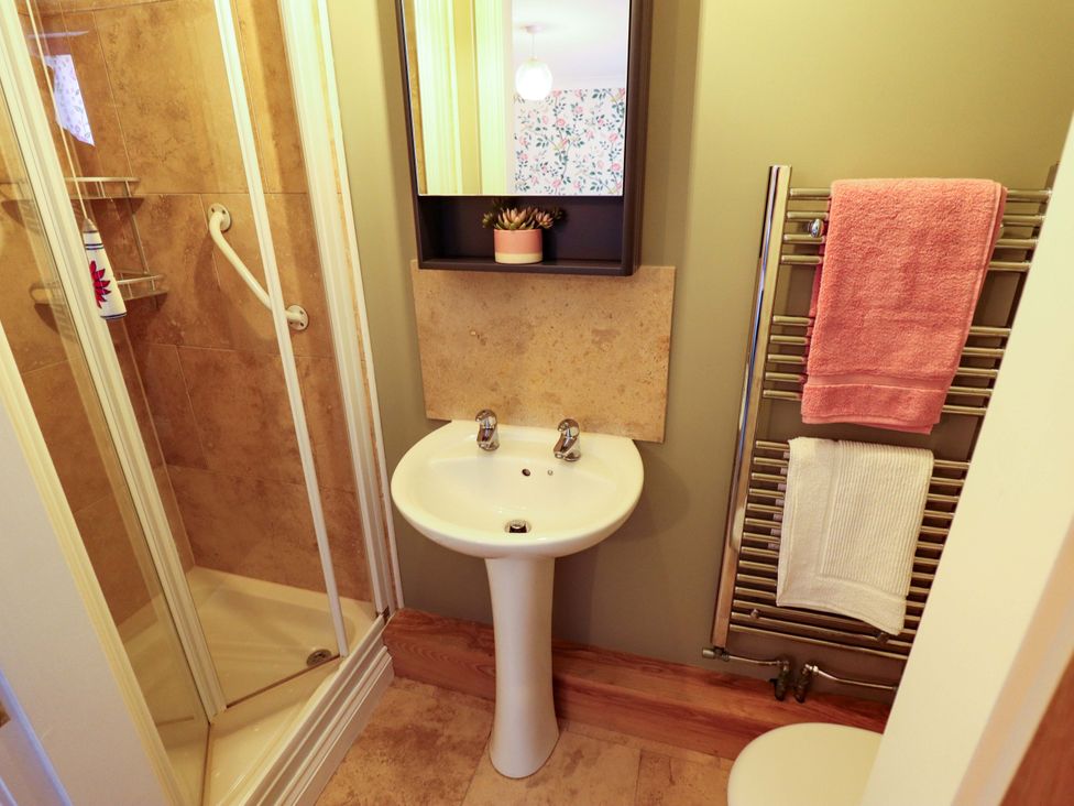 A bathroom featuring a shower, sink, and towel rack at Rowan Cottage in Boston
