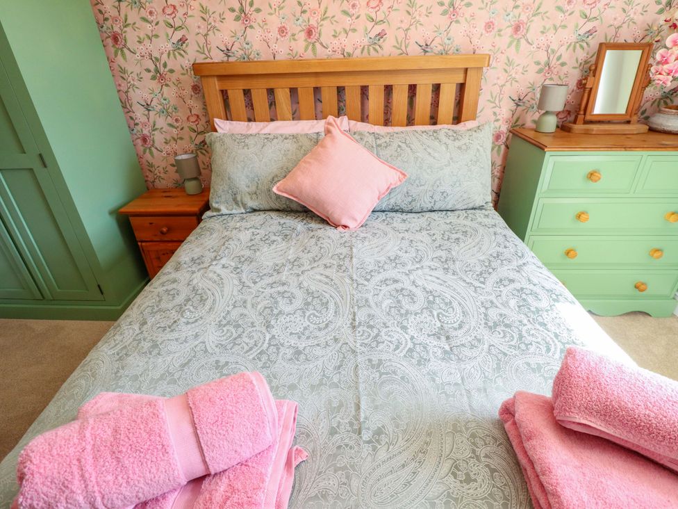 A bedroom with a bed and dresser at Rowan Cottage in Boston