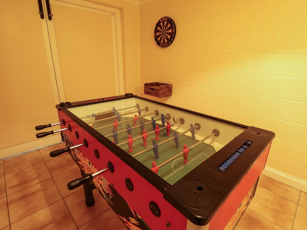 A foosball table with a dartboard in a game room at Rowan Cottage in Boston