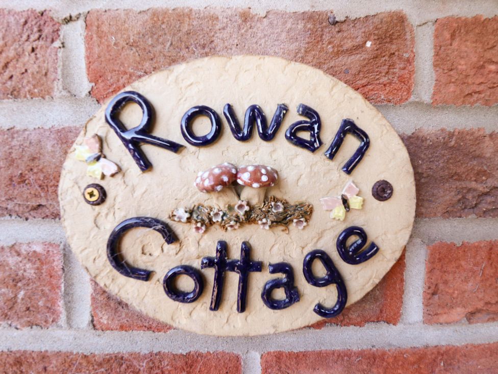 A sign reading 'Rowan Cottage' on a brick wall at Rowan Cottage in Boston