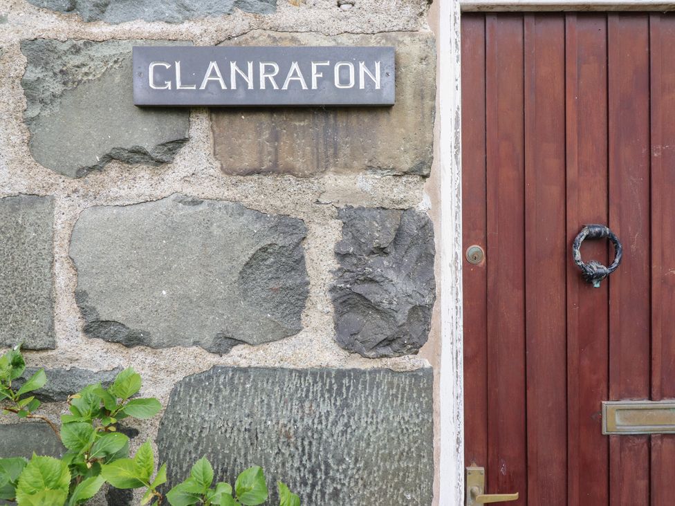 A door with stone wall and an address plaque at Glanrafon