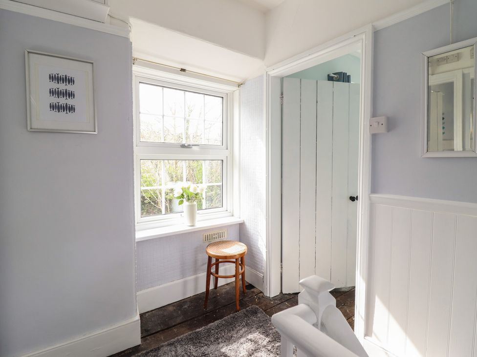 A room with a window, plant, stool, and door at Glanrafon