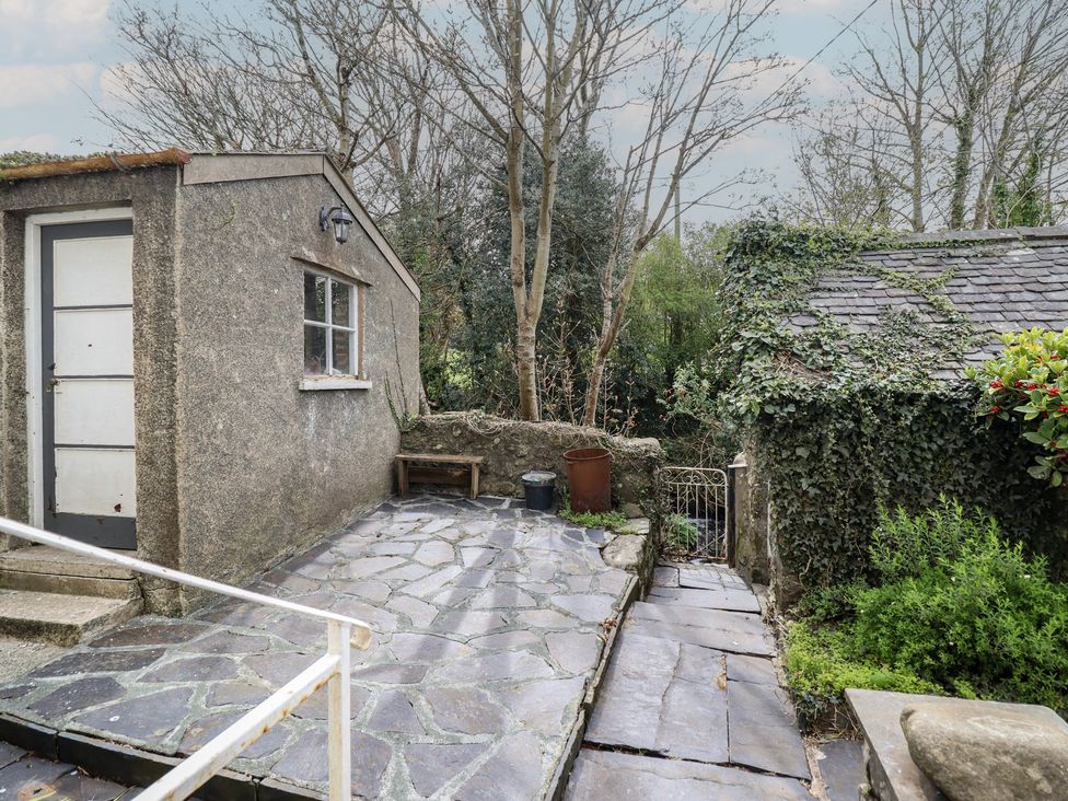 A garden with a shed and paved area at Glanrafon