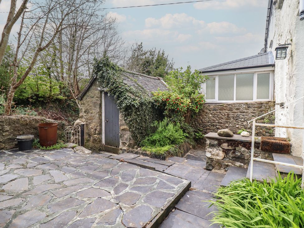 A garden with a stone shed and paving stones at Glanrafon