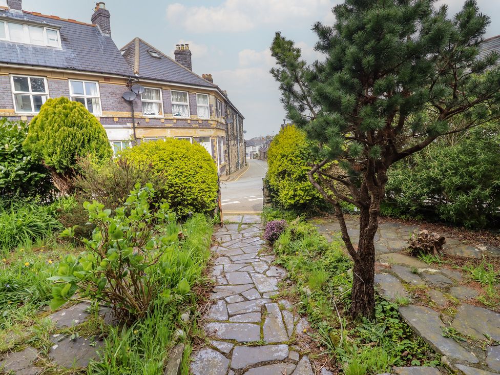 A garden with a stone pathway and bushes at Glanrafon