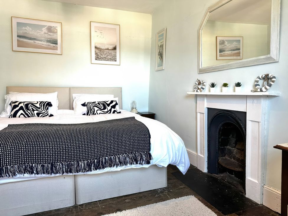A bedroom with a bed and a fireplace at Glanrafon in Llwyngwril