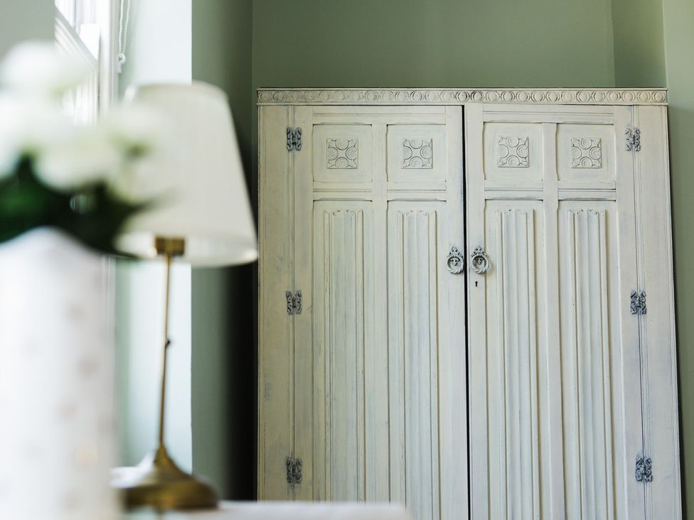 A wardrobe with a lamp and flowers on a table at Admirals home in 