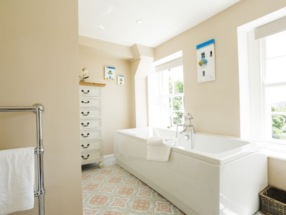 A bathroom with a bathtub and a dressing table at Admirals home in 
