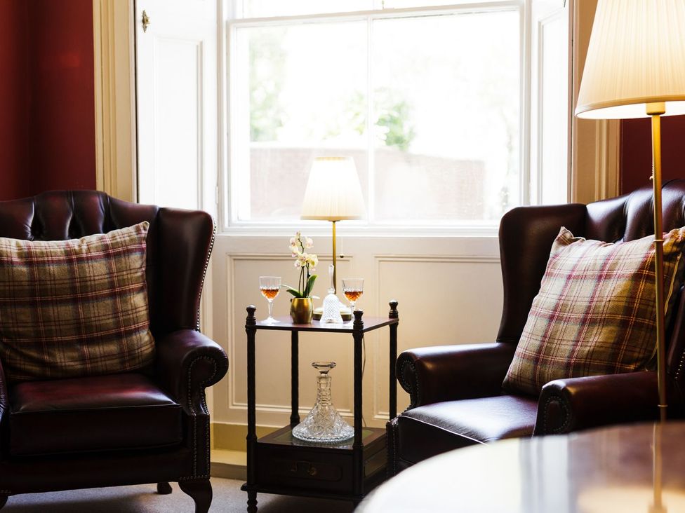 A sitting room with wingback chairs and a table at Admirals home