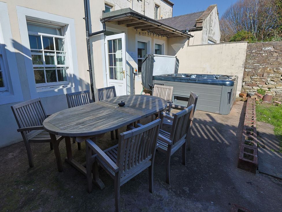 An outdoor seating area with a table and chairs next to a hot tub at Admirals home