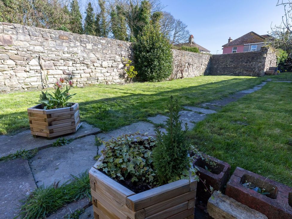 A garden with flower pots and a stone wall at Admirals home