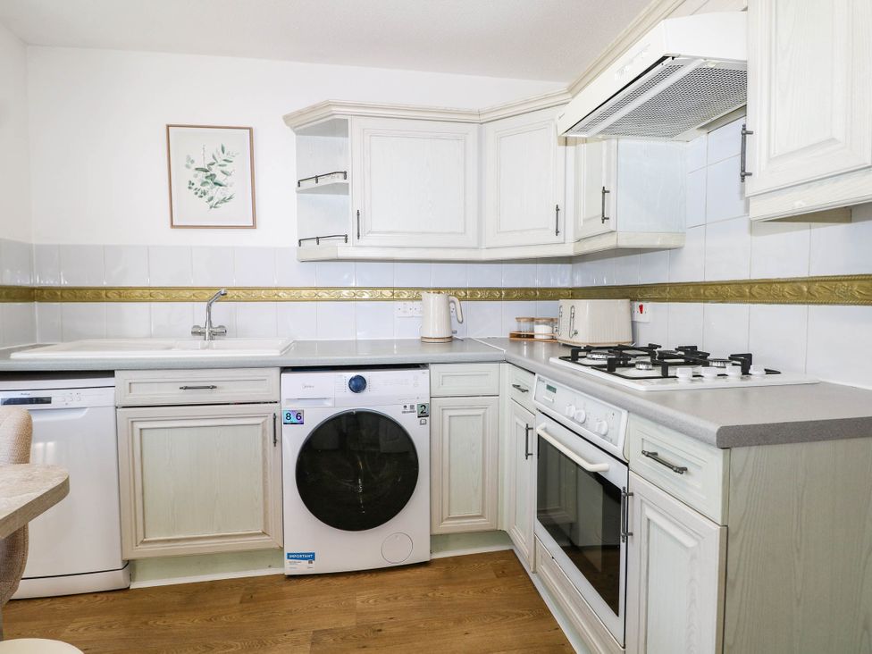 A kitchen with a washing machine and gas stove at 4 Atlantic Close in Southampton