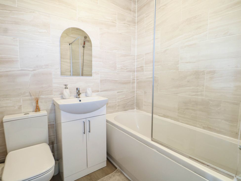 A bathroom with a toilet, sink, mirror, and bathtub at 4 Atlantic Close Southampton