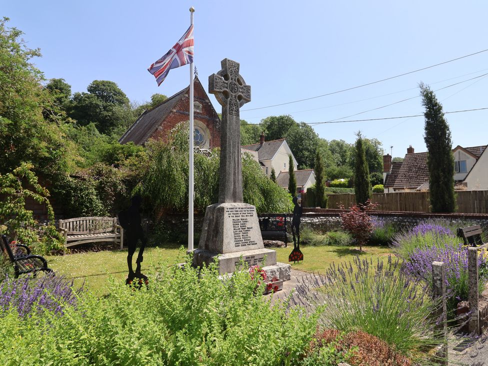 A garden with a memorial cross and benches at Tane in Winterborne Stickland
