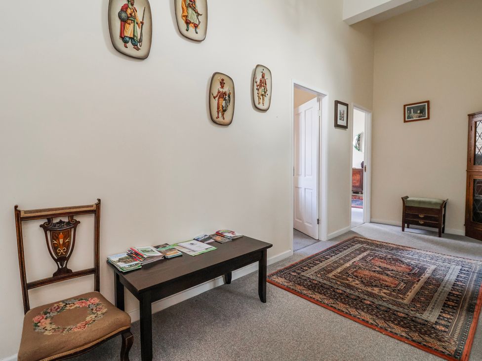 A hallway with a chair and table displaying brochures at Top floor apartment 