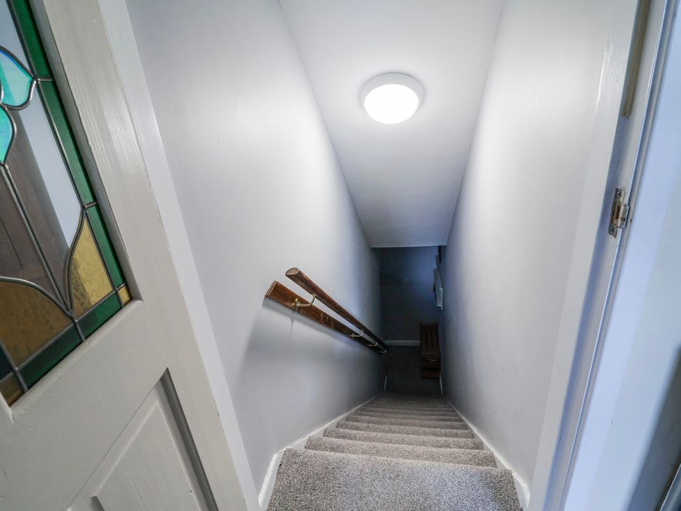 A stairway with a handrail and light fixture at Top floor apartment