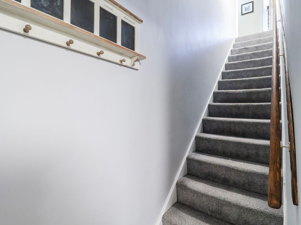 A staircase with a handrail and a wall with hooks at Top floor apartment 