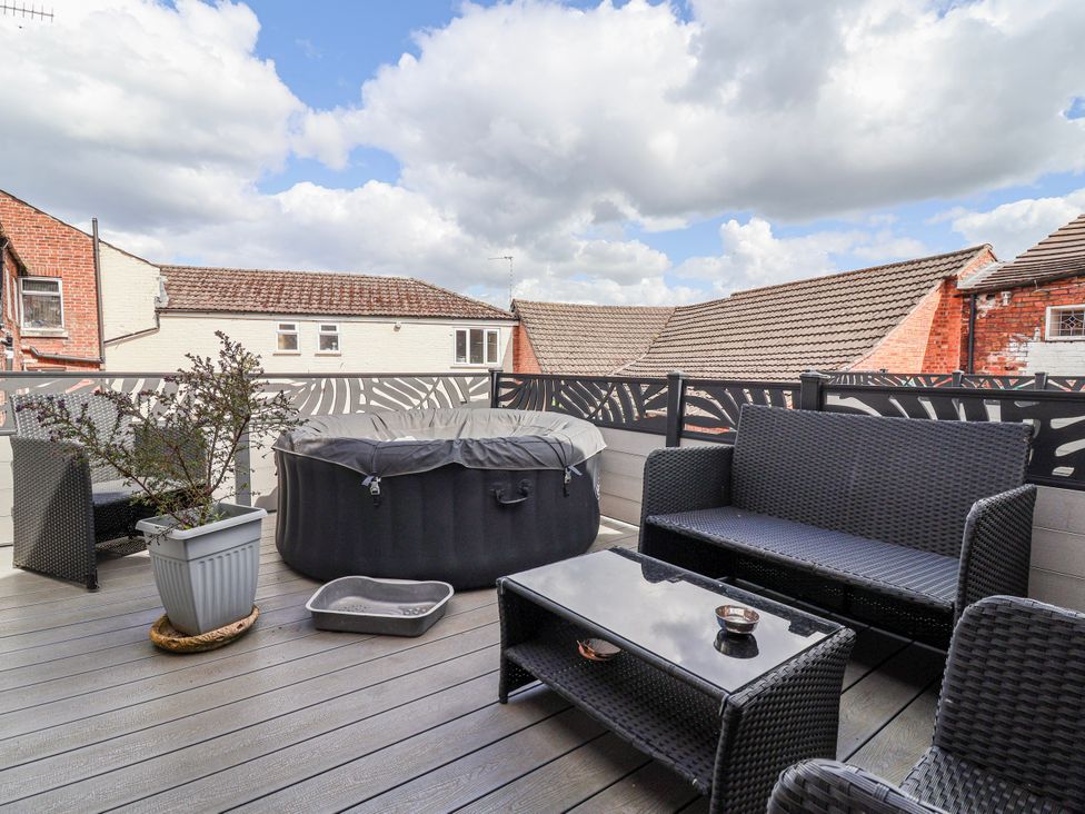 An outdoor terrace with a hot tub and seating at Top floor apartment