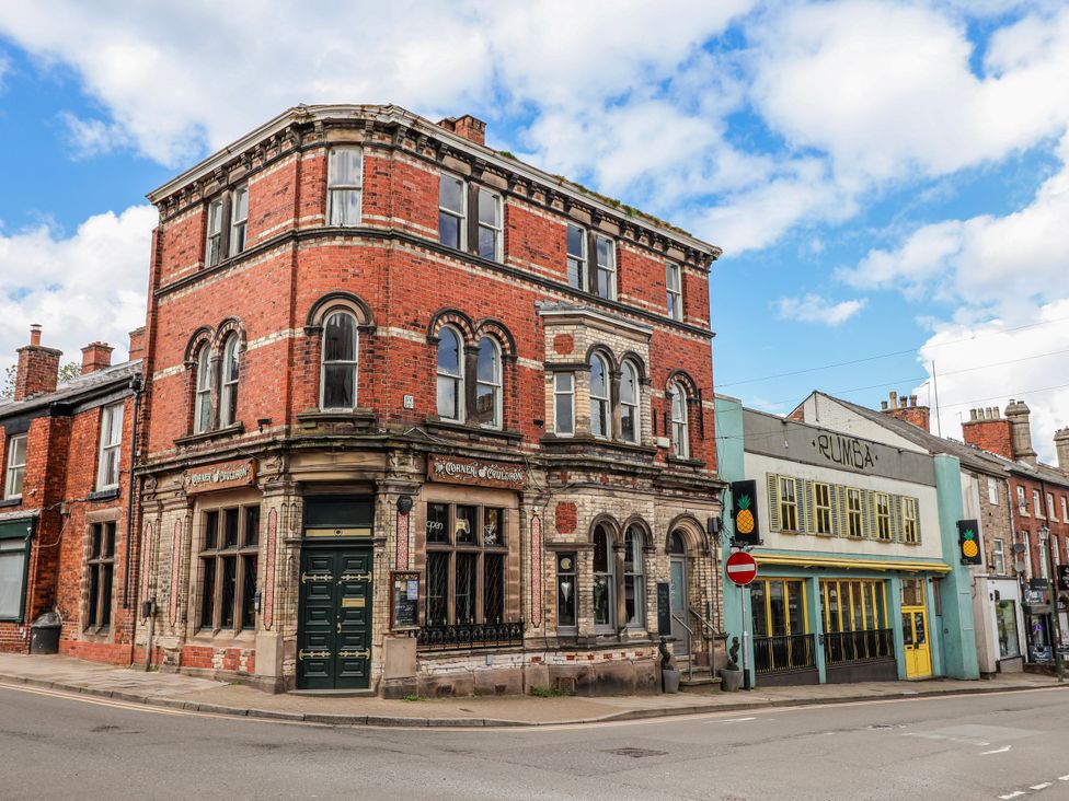 A street view of buildings and shops including Corner and Rumba in a town