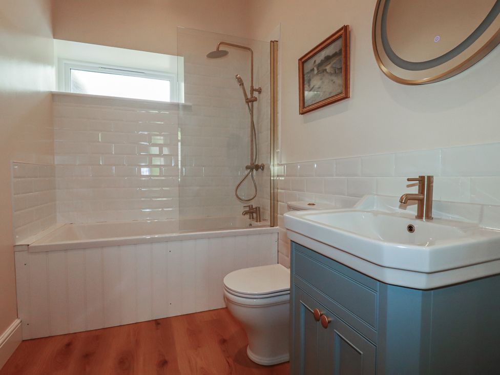 A bathroom with a bathtub, shower, sink, and toilet at Farthings, The Old Chapel in St. Austell