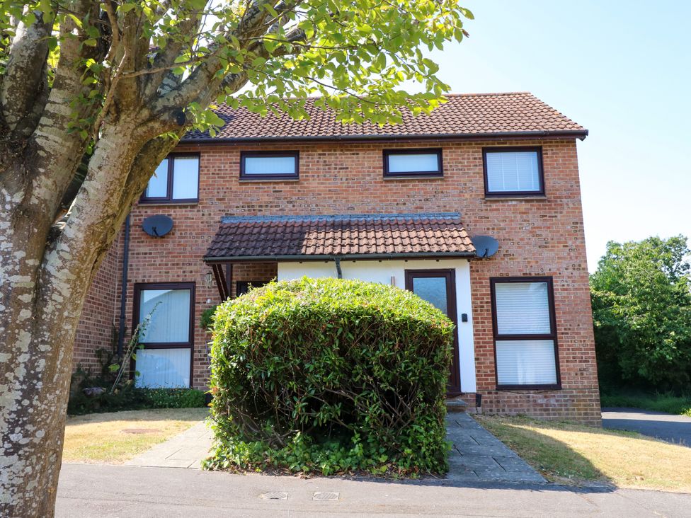 A house with a bush and tree at 73 Pennywell Gardens in New Milton