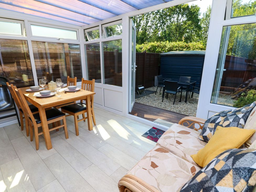 A conservatory with a dining table and sofa at 73 Pennywell Gardens in New Milton