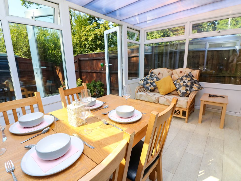 A conservatory with a dining table and sofa at 73 Pennywell Gardens New Milton
