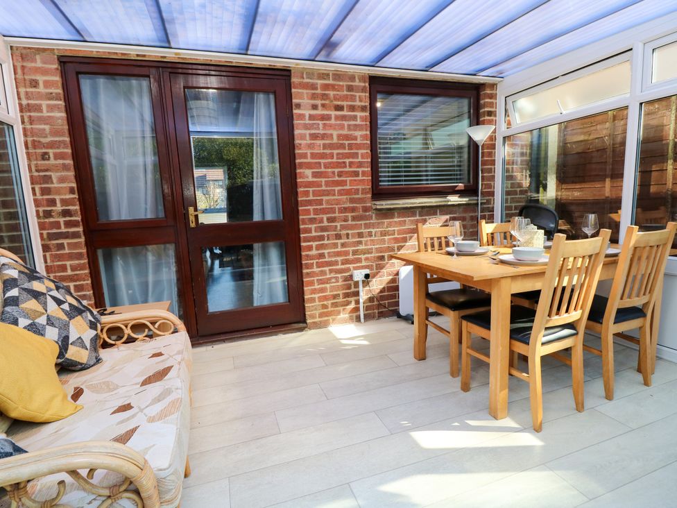A conservatory with a table and chairs at 73 Pennywell Gardens in New Milton