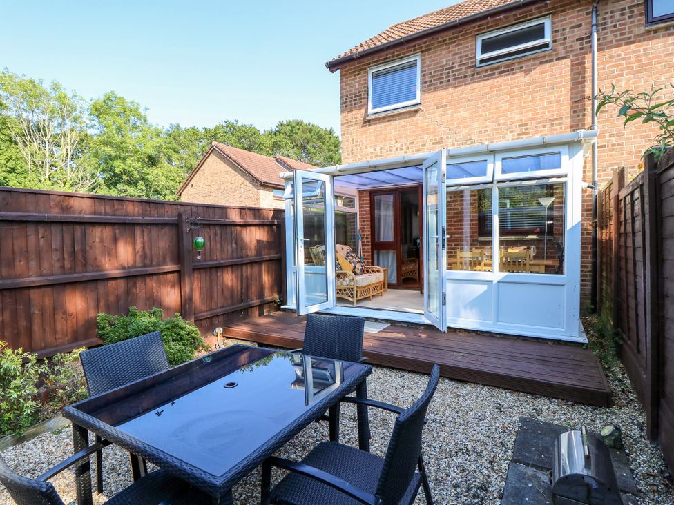 A garden with a conservatory and outdoor table at 73 Pennywell Gardens New Milton