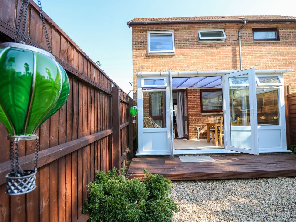 A garden with a back door leading to a dining area at 73 Pennywell Gardens New Milton