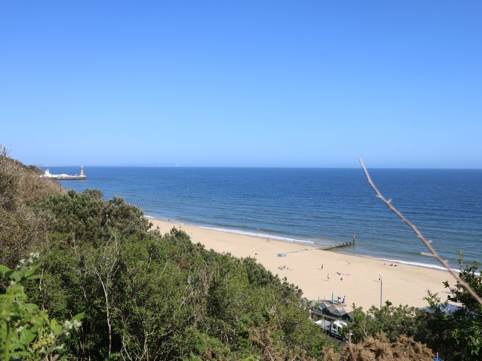 A beach view with a pier and people at 73 Pennywell Gardens New Milton