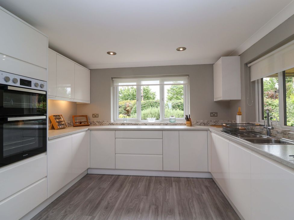 A kitchen with white cabinets and a window overlooking a garden at 26 Five Bells in Watchet