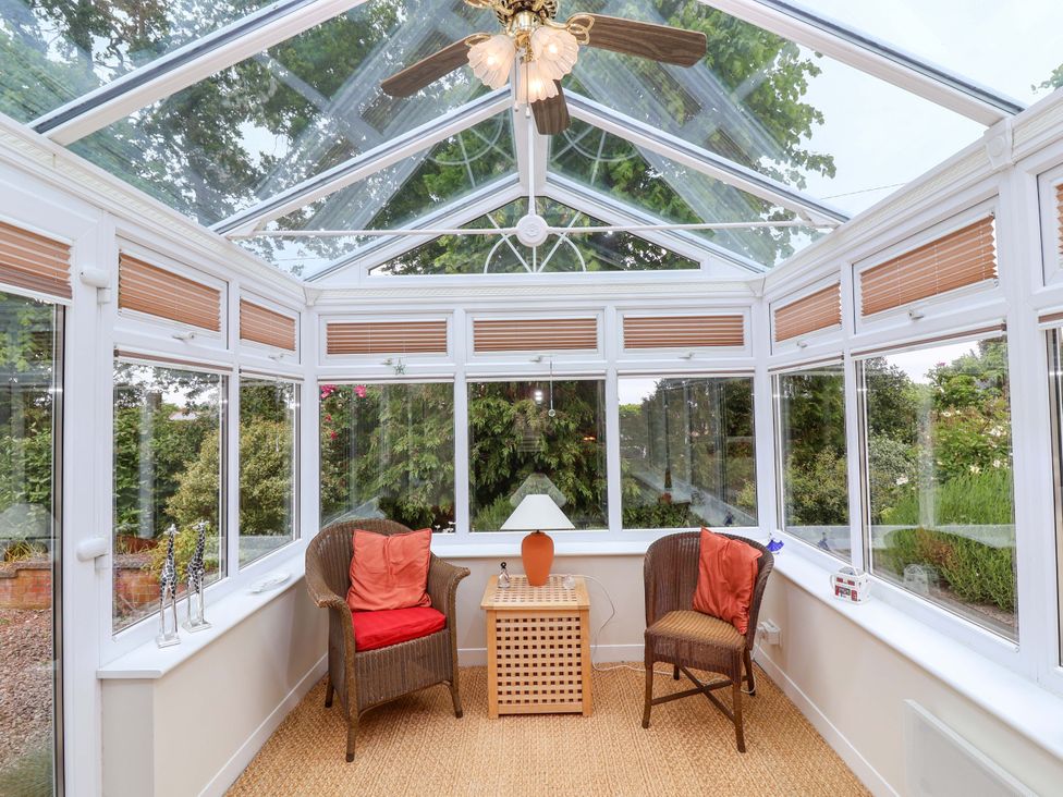 A conservatory with two armchairs and a table at 26 Five Bells in Watchet