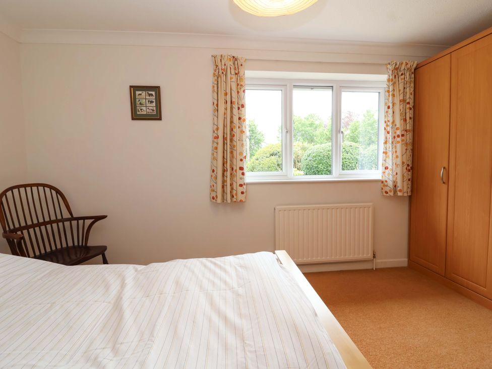 A bedroom with a bed, wardrobe, chair, and window at 26 Five Bells Watchet