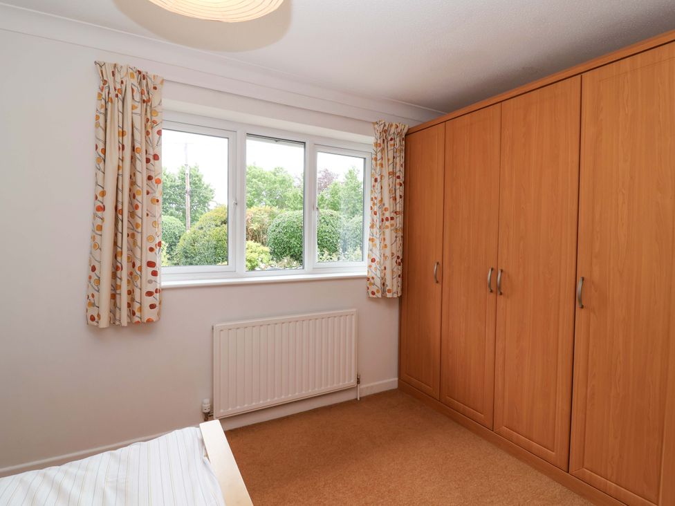 A bedroom with a wardrobe and window at 26 Five Bells Watchet